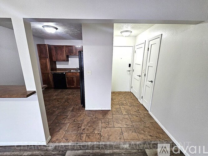 A kitchen area with brown cabinets and a black refrigerator.