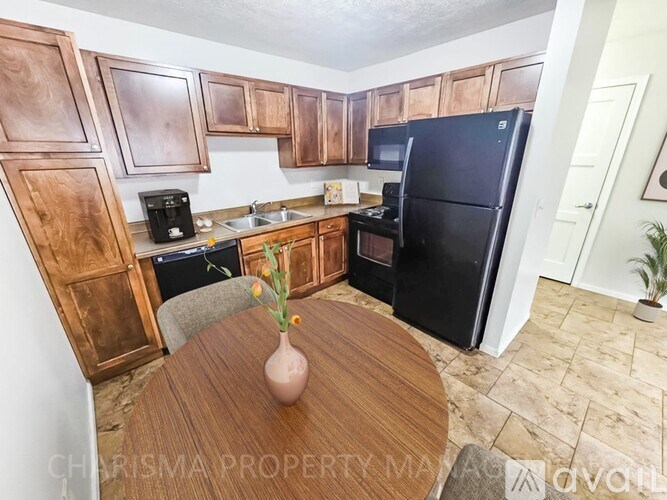 A kitchen with wooden cabinets and a black refrigerator.