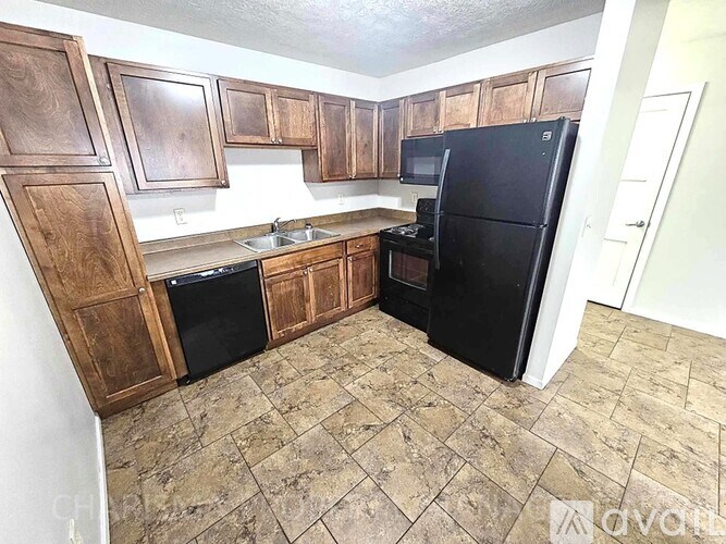 A kitchen with wooden cabinets and a black refrigerator.