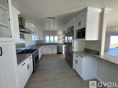 A kitchen with white cabinets and granite countertops.