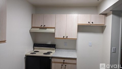 A small kitchen with a black oven and wooden cabinets.