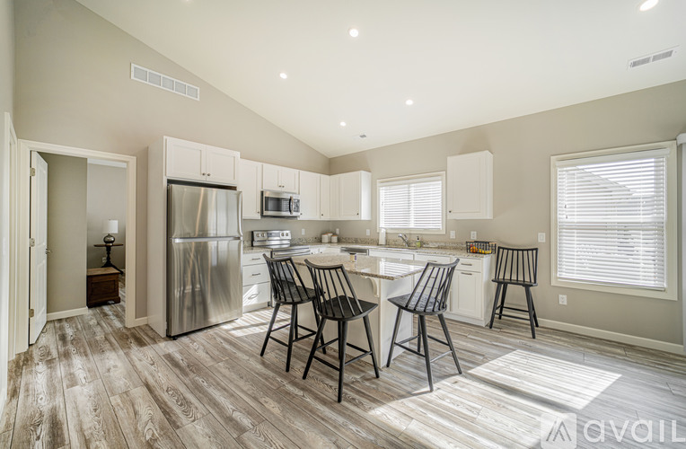 A kitchen with a refrigerator, sink, and dining table.