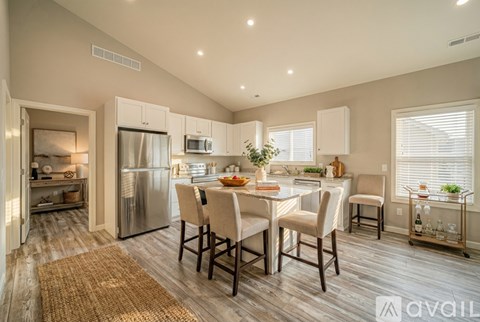 A kitchen with a refrigerator, sink, and dining table.