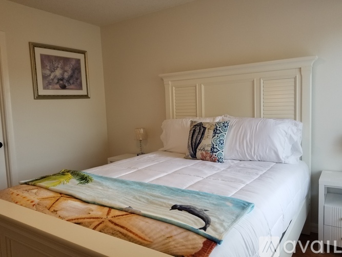 A bed with a white comforter and a picture frame on the wall.