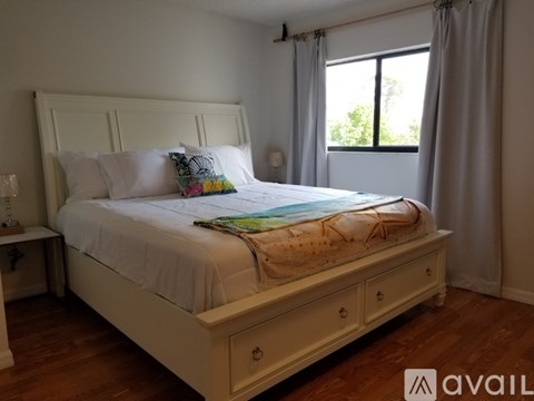 A bedroom with a large bed and a window with curtains.