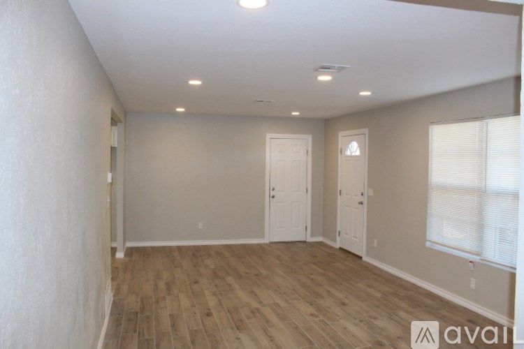 A spacious room with wooden flooring and white walls.