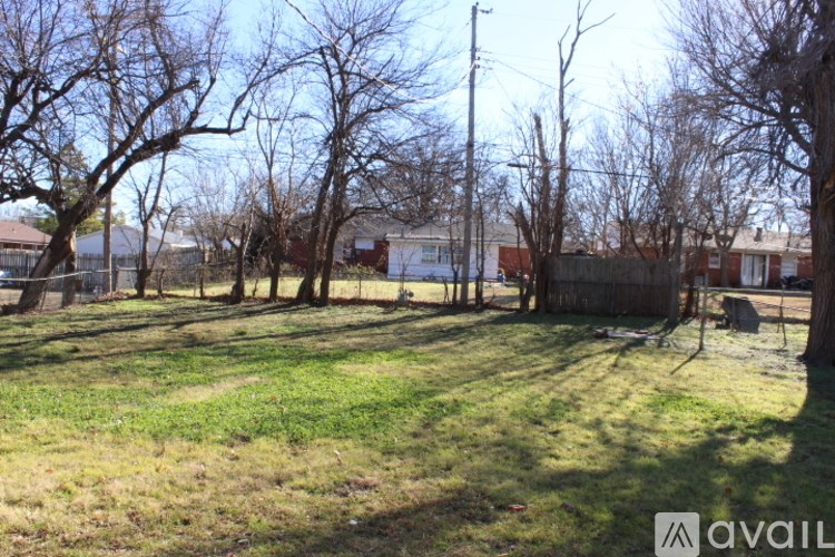 A grassy area with trees and houses in the background.