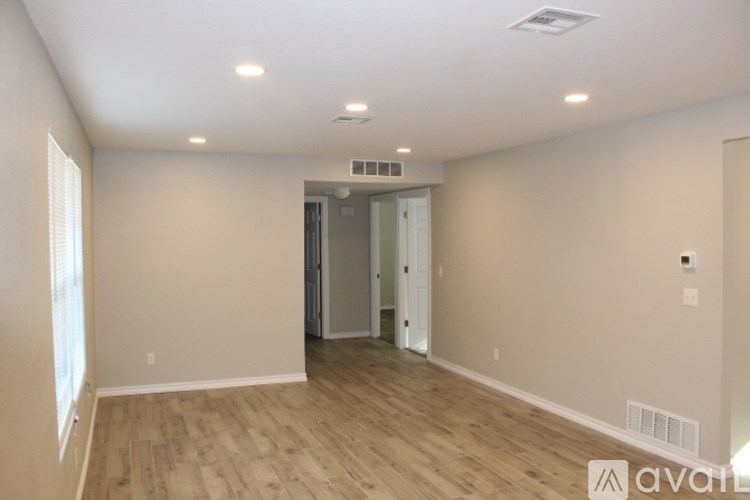 A spacious room with wooden flooring and a doorway leading to another room.