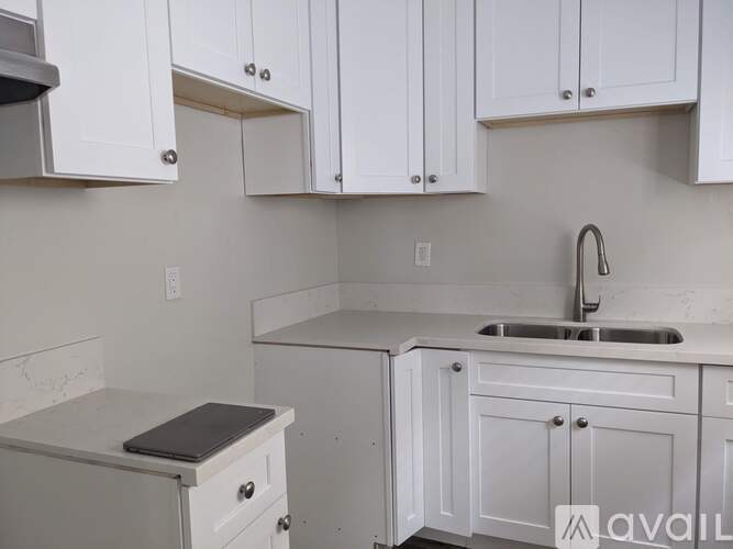 A kitchen with white cabinets and a marble countertop.