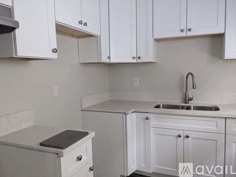 A kitchen with white cabinets and a marble countertop.