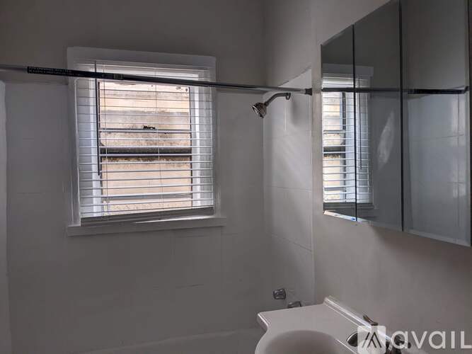 A bathroom with a window covered in blinds.