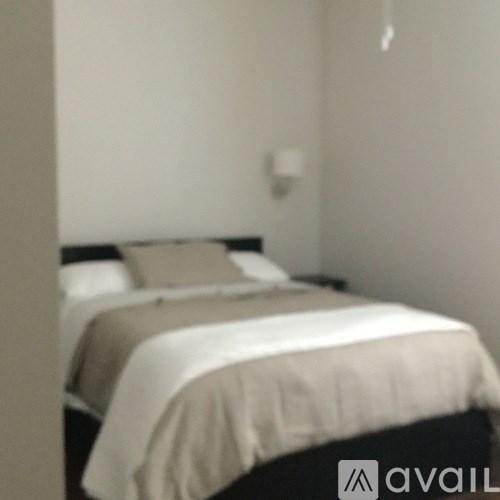 A bed with a white sheet and a grey pillowcase is in the image.