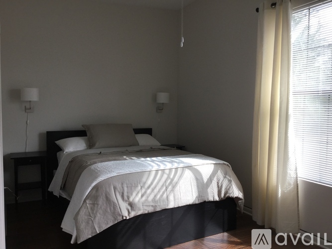 A bedroom with a large bed and two lamps on either side of the bed.
