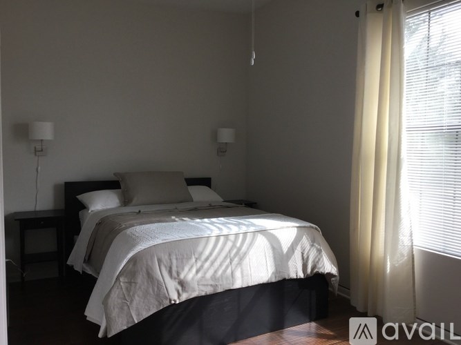 A bedroom with a large bed and two lamps on either side of the bed.