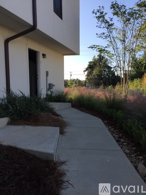 A white house with a brown door and a brown pipe on the side.