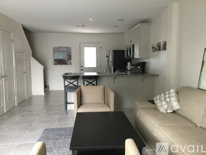A living room with a couch, a table, and a kitchen area in the background.