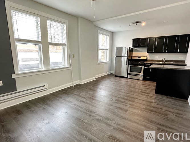 A kitchen with black cabinets and a wooden floor.