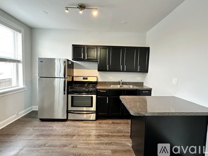 A kitchen with black cabinets and a stainless steel refrigerator.