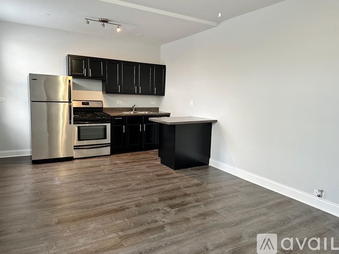 A kitchen with black cabinets and a wooden floor.
