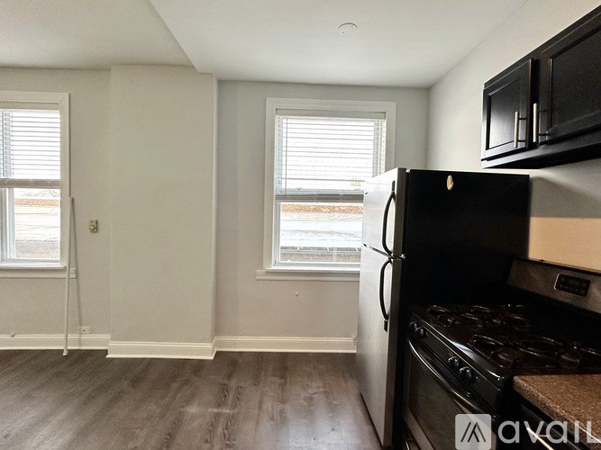 A kitchen with a black fridge and stove top oven.