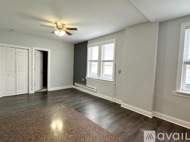 A room with a ceiling fan and a rug on the floor.