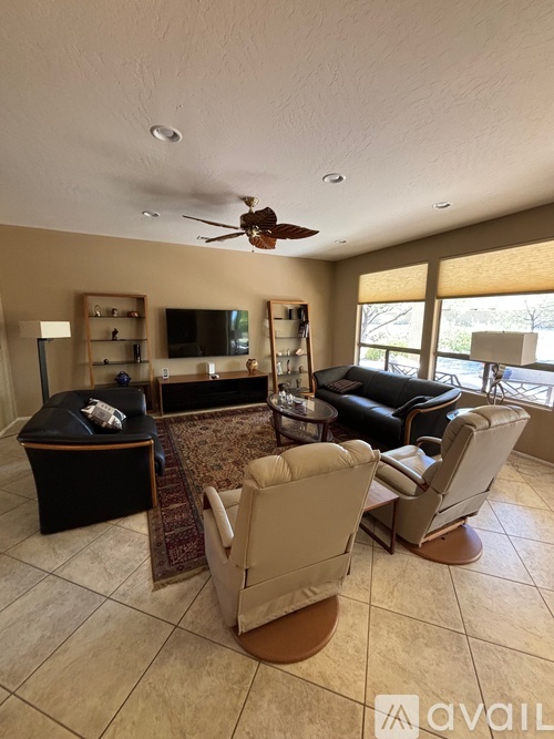 A living room with a black ottoman and a brown rug.