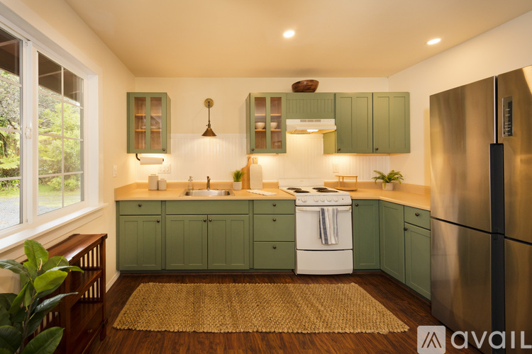 A kitchen with green cabinets and a white dishwasher.