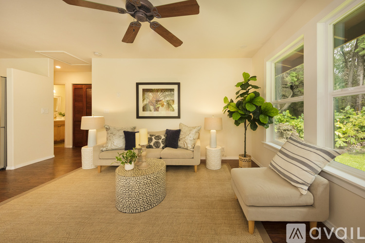 A living room with a white couch, a brown rug, and a ceiling fan.