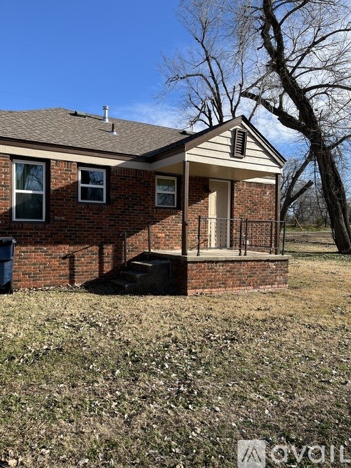 A small brick house with a black grill on the front lawn.