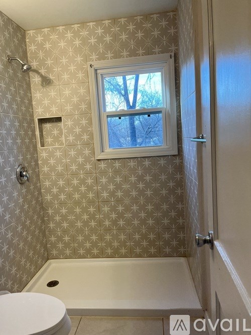 A bathroom with a toilet, tub, and window.