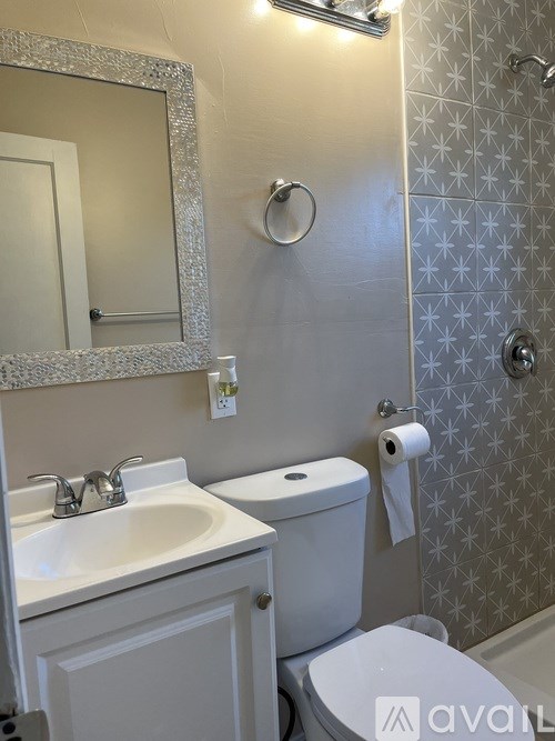 A bathroom with a toilet, sink, mirror, and shower.