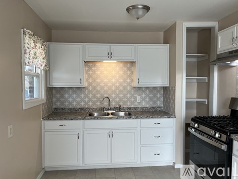 A kitchen with white cabinets and a patterned backsplash.