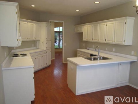 A kitchen with white cabinets and a wooden floor.