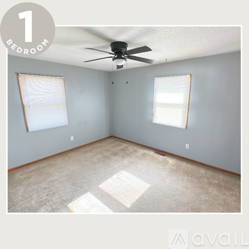 A bedroom with a ceiling fan and two windows.
