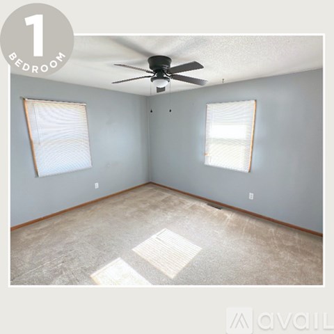 A bedroom with a ceiling fan and two windows.