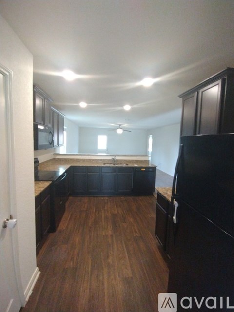 A kitchen with black cabinets and a wooden floor.