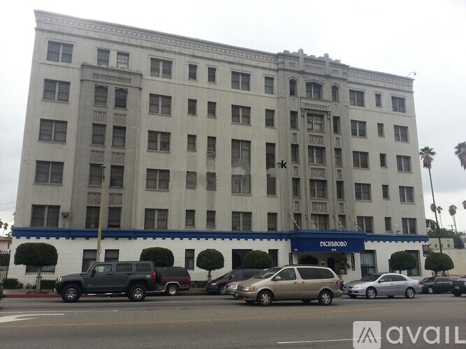 A large building with a blue awning and cars parked in front.