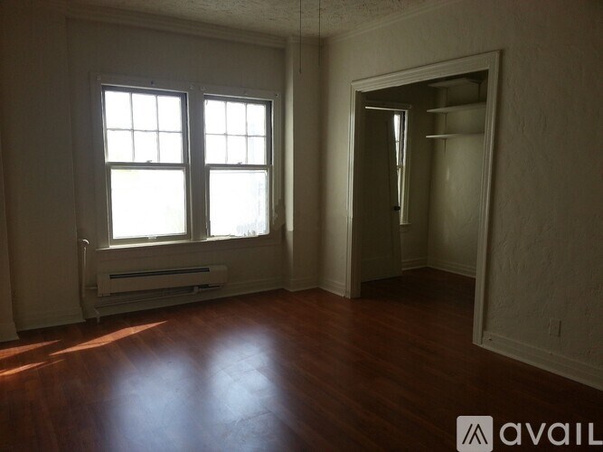 A room with wooden floors and a window with blinds.