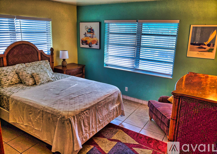 A bedroom with a bed, a bench, and a painting on the wall.