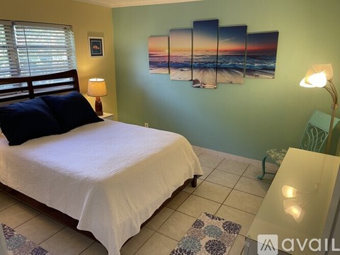 A bedroom with a bed, a bench, and a painting on the wall.