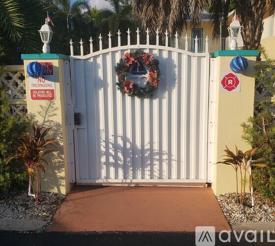 A white gate with a wreath and a sign that says "No Trespassing" is closed.