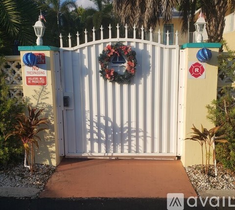 A white gate with a wreath and a sign that says "No Trespassing" is closed.