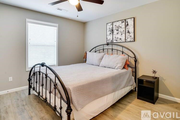 A bedroom with a bed, a ceiling fan, and a window with blinds.