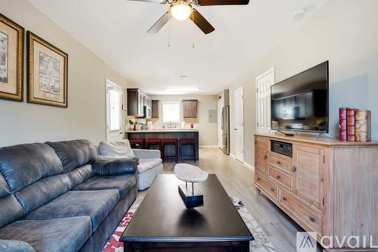A living room with a black leather couch and a flat screen TV on a wooden cabinet.