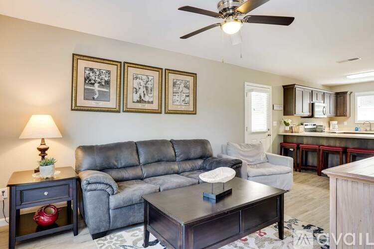 A living room with a grey couch, a coffee table, and a ceiling fan.