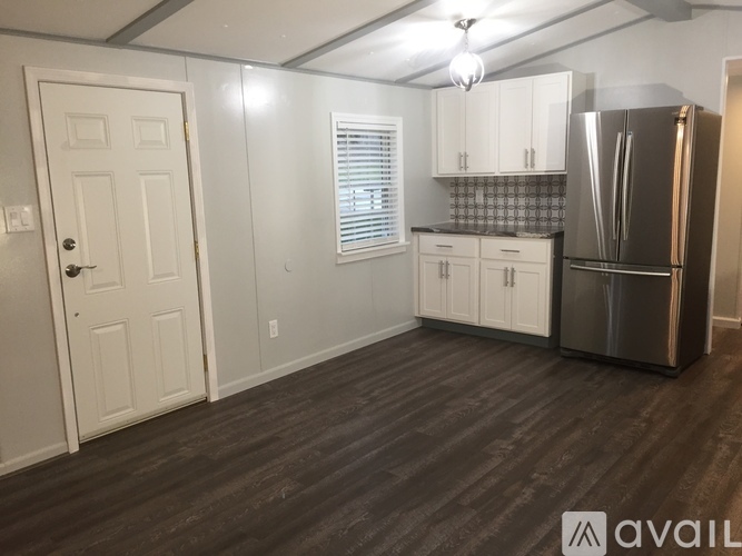 A kitchen with white cabinets and a stainless steel refrigerator.