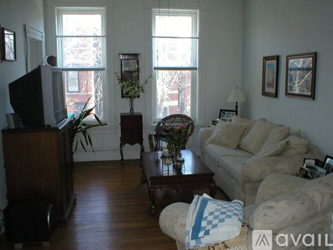 A living room with a couch, a chair, a coffee table, and a television.