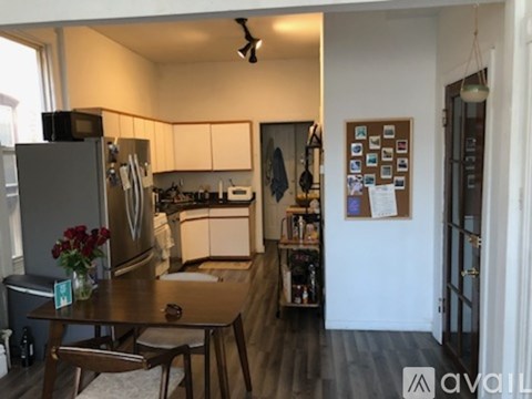 A kitchen with a refrigerator, table, and chairs.