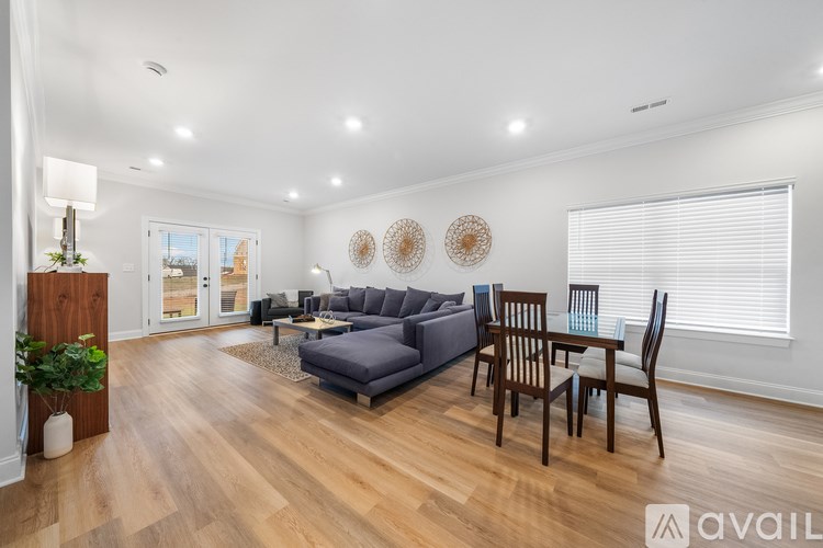 A living room with a grey sofa, wooden chairs, and a glass table.