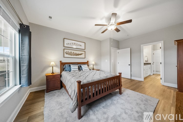 A bedroom with a bed, a ceiling fan, and a window with curtains.